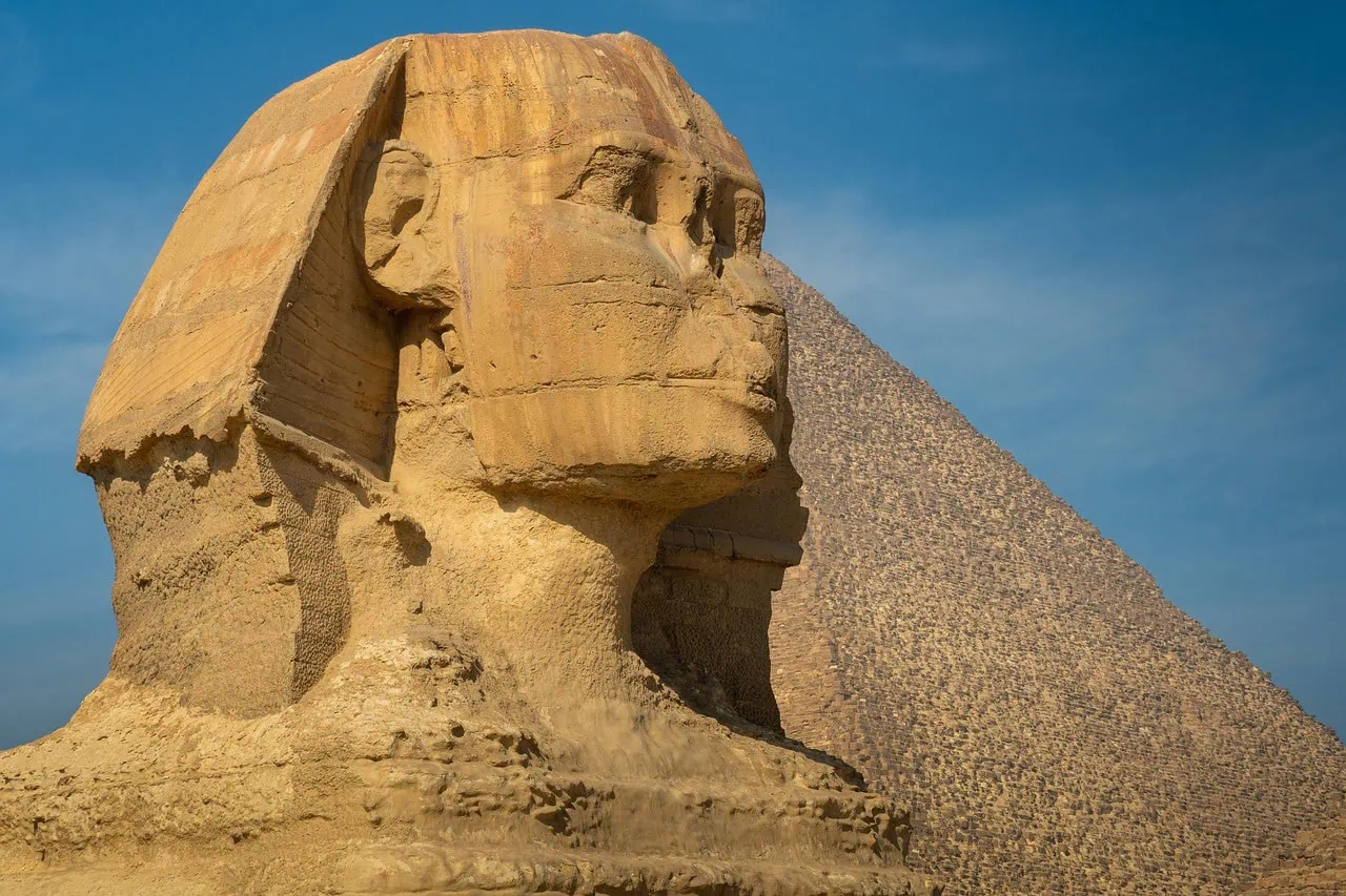 Great Sphinx of Giza with pyramid in the background under clear sky