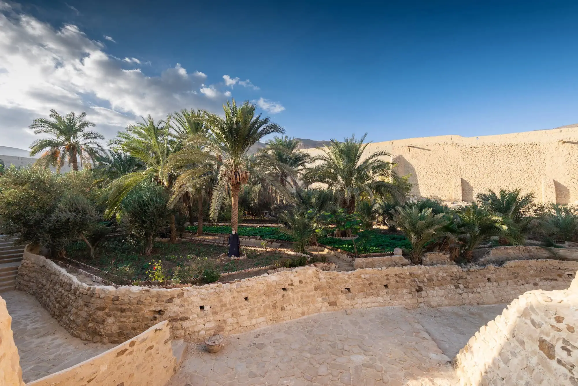 High-angle view of Saint Paul Monastery garden with terraced stone walls and palm trees