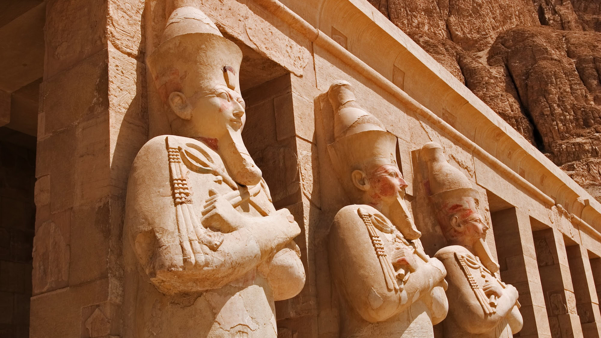 Ancient Egyptian temple facade with pharaoh statues, columns, and hieroglyphic carvings