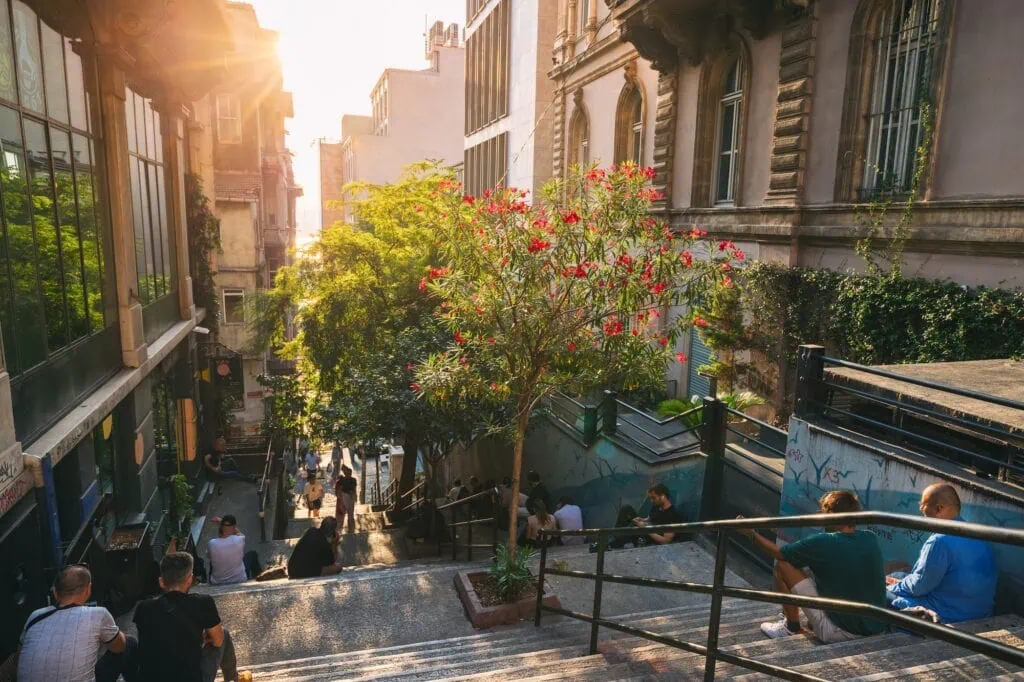 People resting on stone steps along a street in the Pera district at sunset, Istanbul
