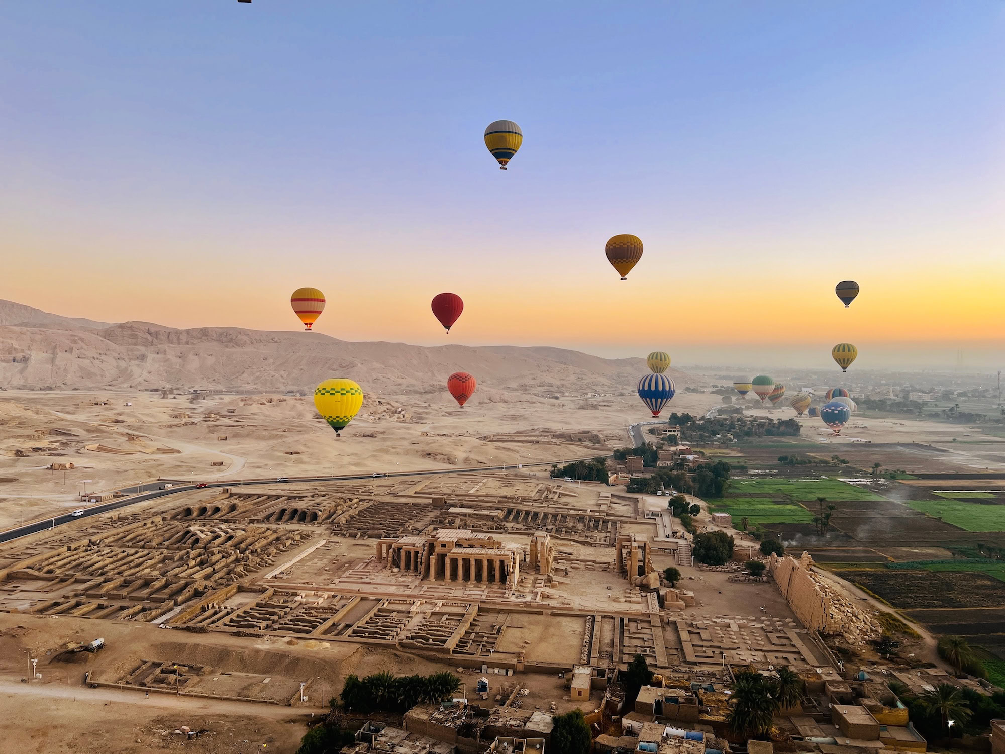 Hot air balloons drifting above Luxor’s Valley of the Kings, offering views of ancient temples, fertile fields, and desert cliffs
