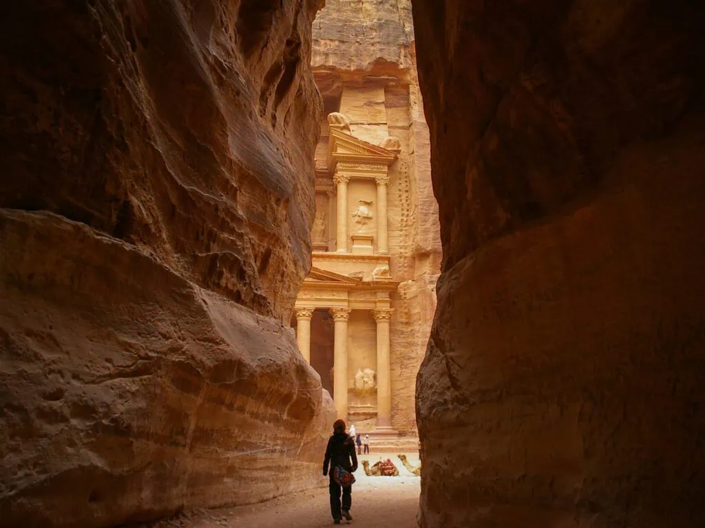 The view of Al-Khazneh (The Treasury) at Petra emerging through the narrow Siq canyon, Jordan — the dramatic first reveal of Petra's most famous Nabataean facade after a 1.2 km walk through the sandstone gorge - Egypt and Jordan Tours