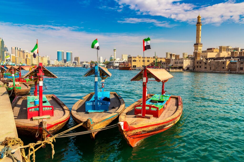 Traditional wooden abra boat on Dubai Creek with Grand Bur Dubai Mosque in the background, Dubai