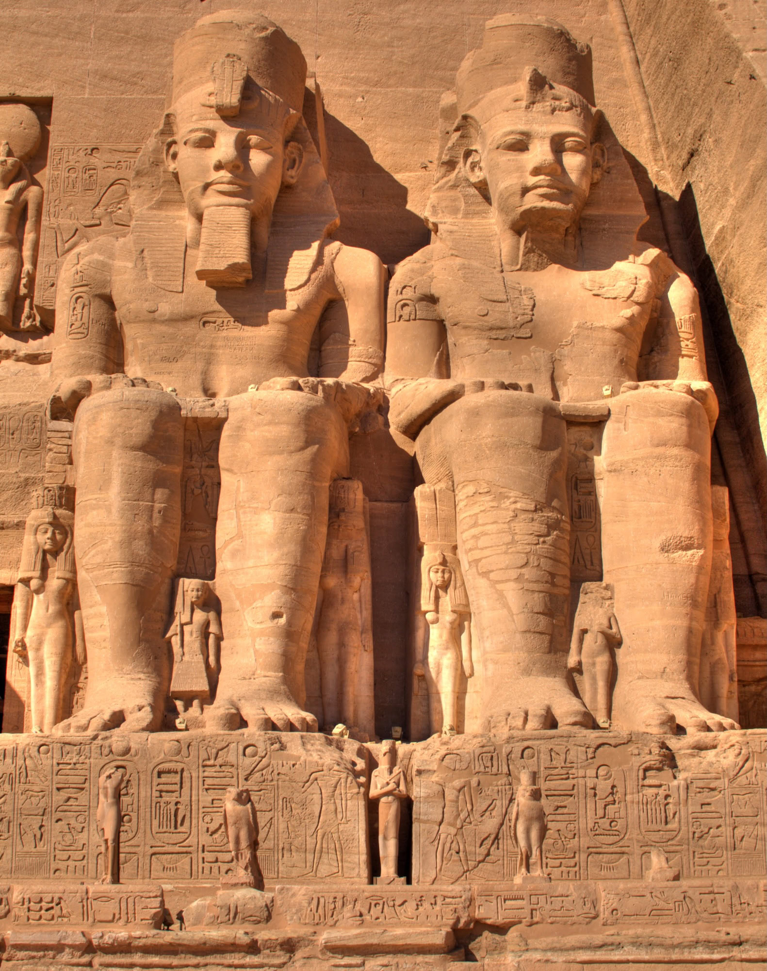 Massive rock-cut pharaoh statues at Abu Simbel temple with hieroglyphics and ancient carvings