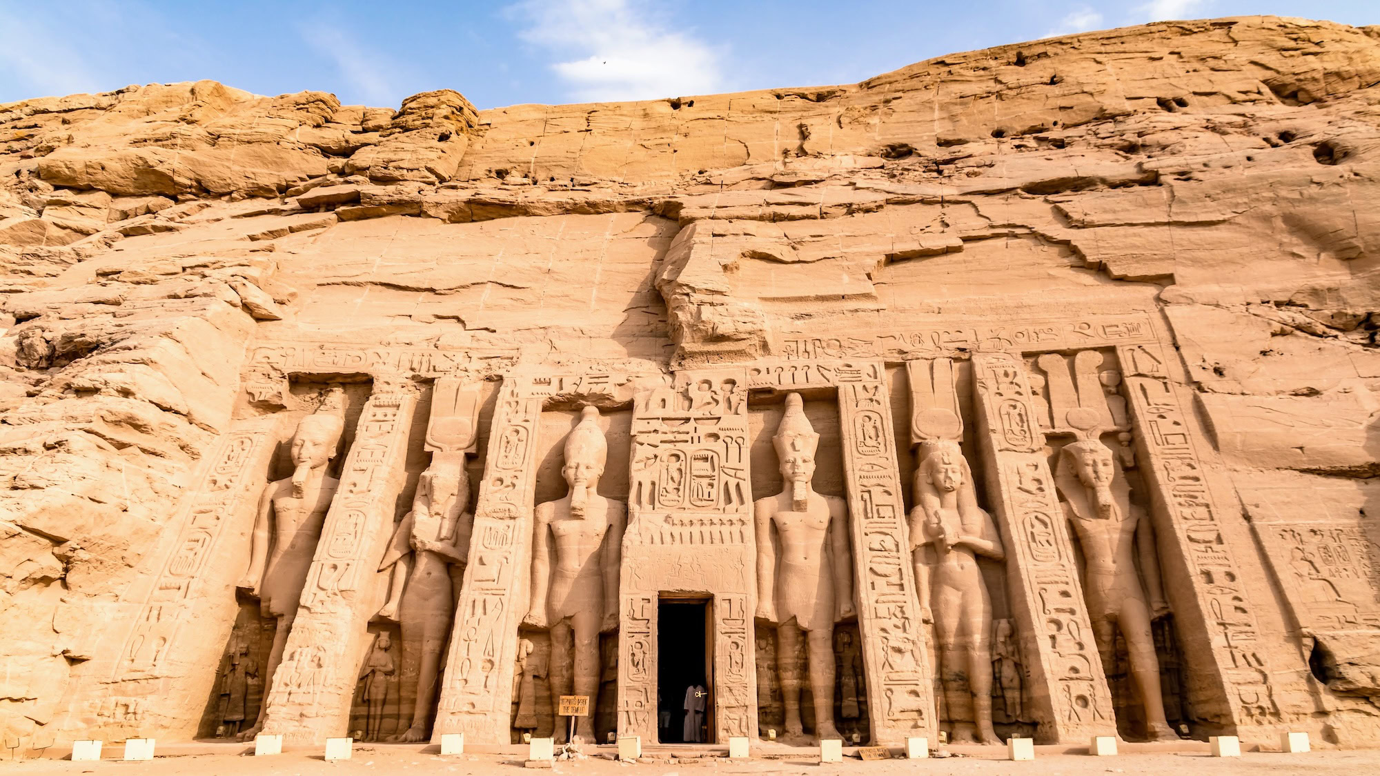 Ancient Abu Simbel temple facade with carved statues and hieroglyphics in sandstone cliff