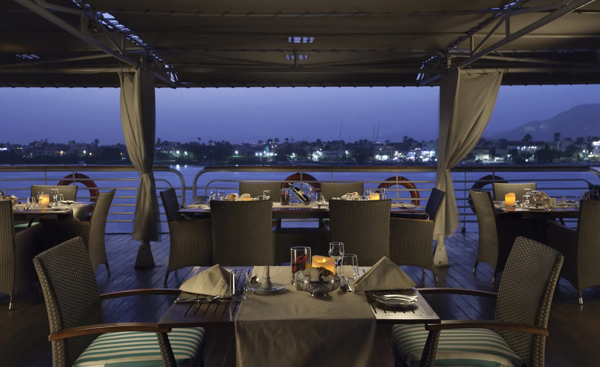 Elegant dining area on Nile River cruise ship with tables and city lights