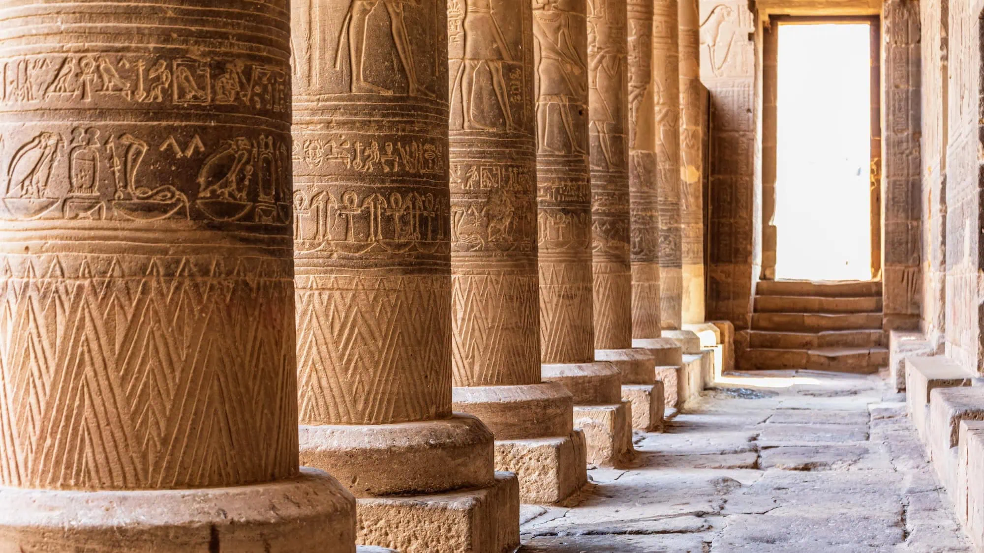 Interior colonnade of ancient Egyptian temple with carved hieroglyphic columns and stone corridor