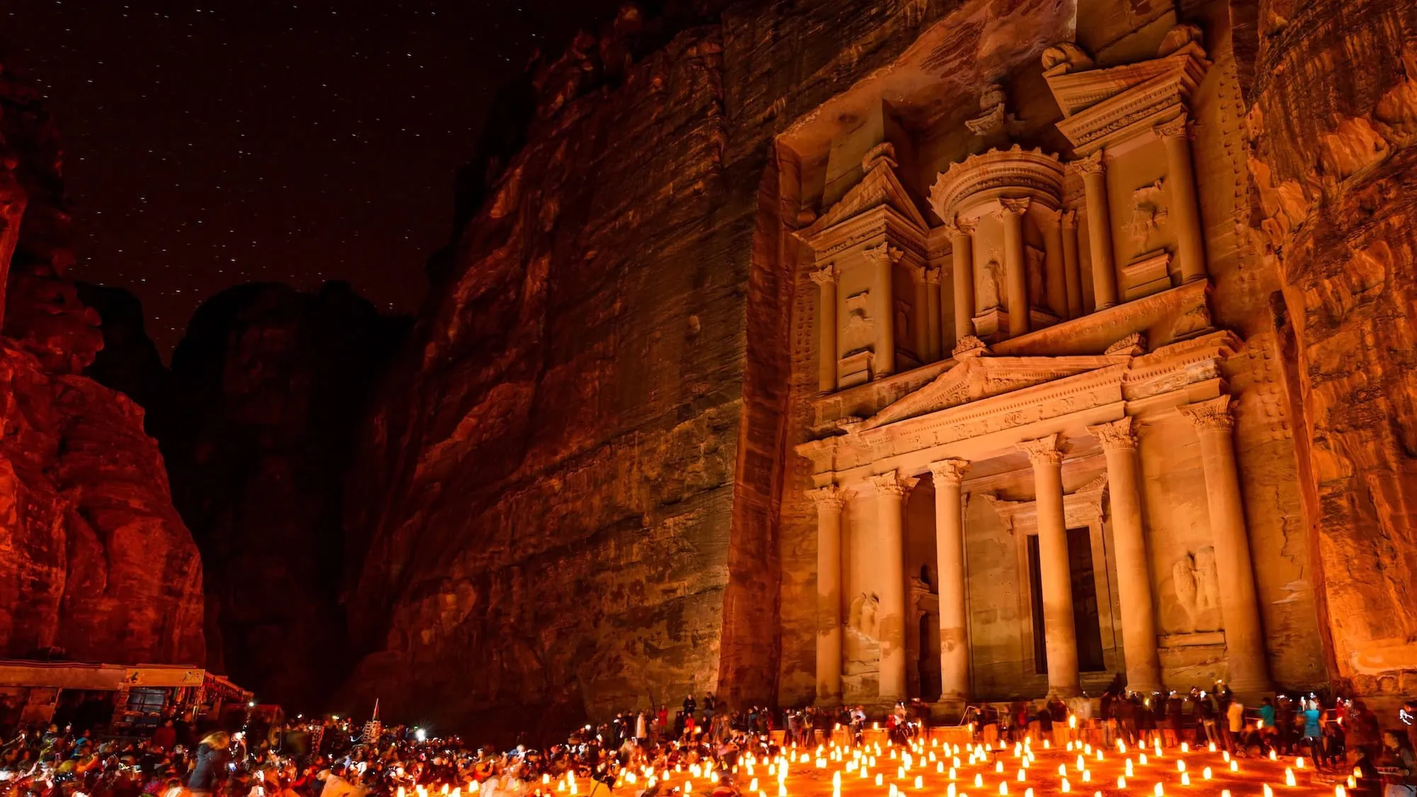 The Treasury at Petra illuminated by candlelight at night with crowds gathered