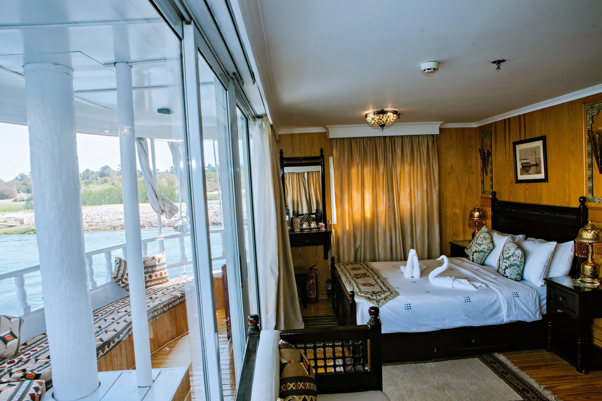 Luxurious cruise ship cabin with chandelier, balcony overlooking the Nile River, and elegant furnishings