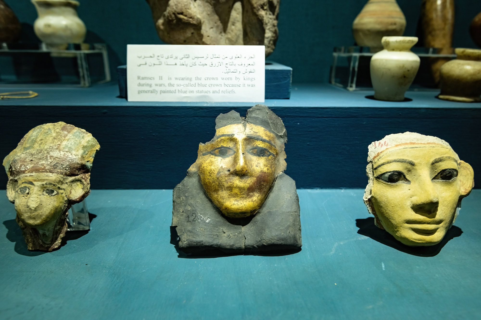 Museum display cases featuring ancient Egyptian masks, pottery, and artifacts