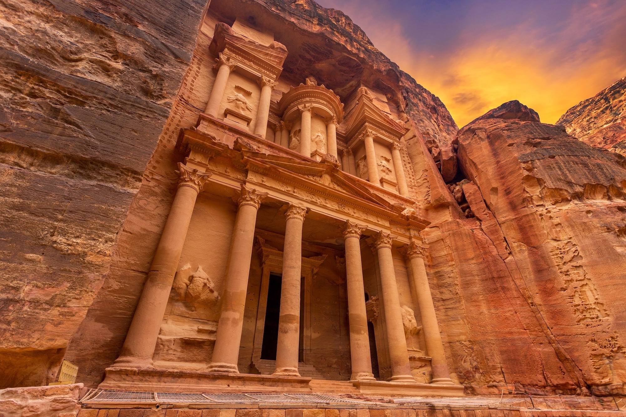 The famous Treasury (Al-Khazneh) in Petra carved into red sandstone cliffs at sunset