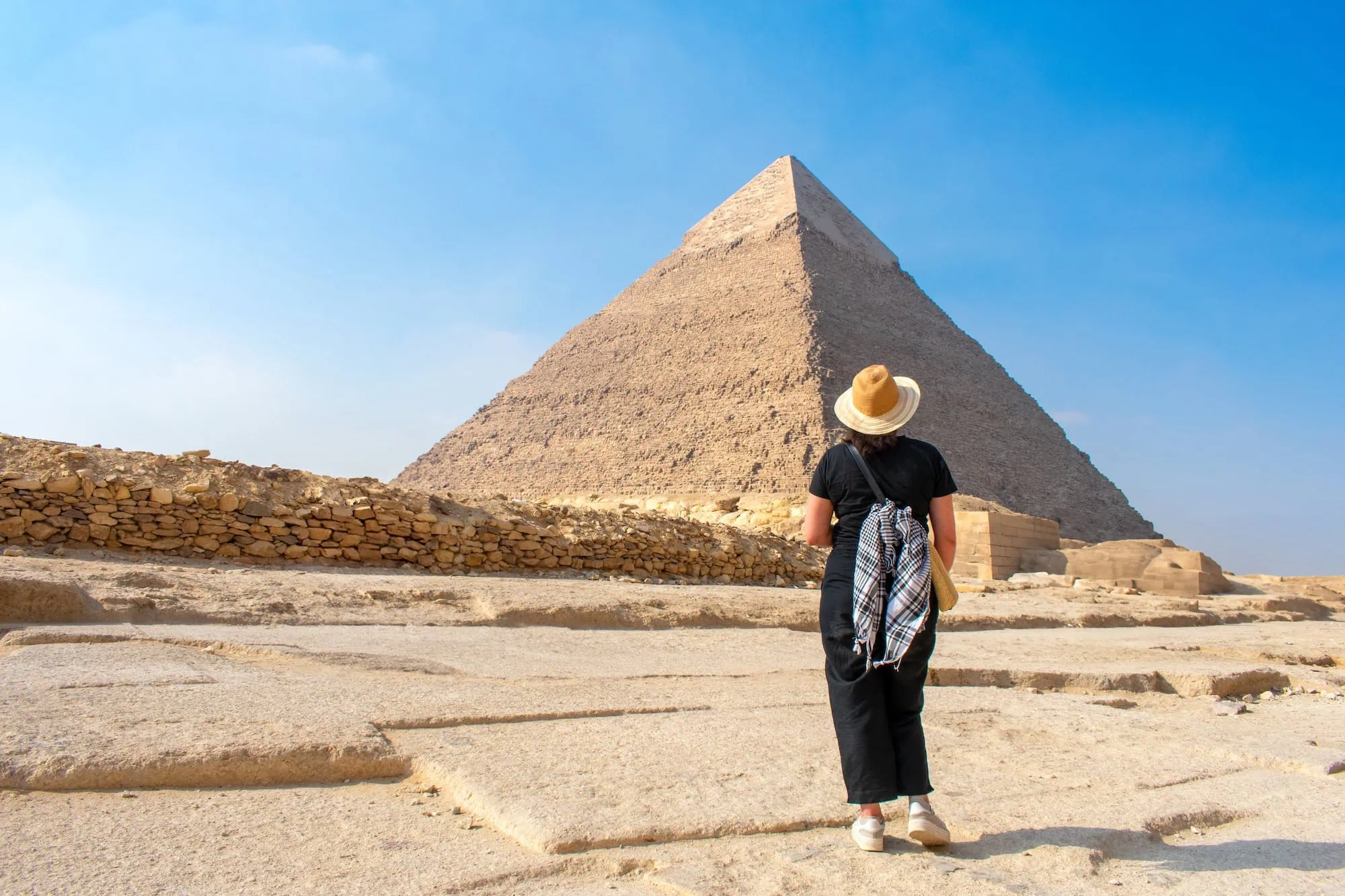 Woman in black clothing standing in contemplation before the Great Pyramid of Giza