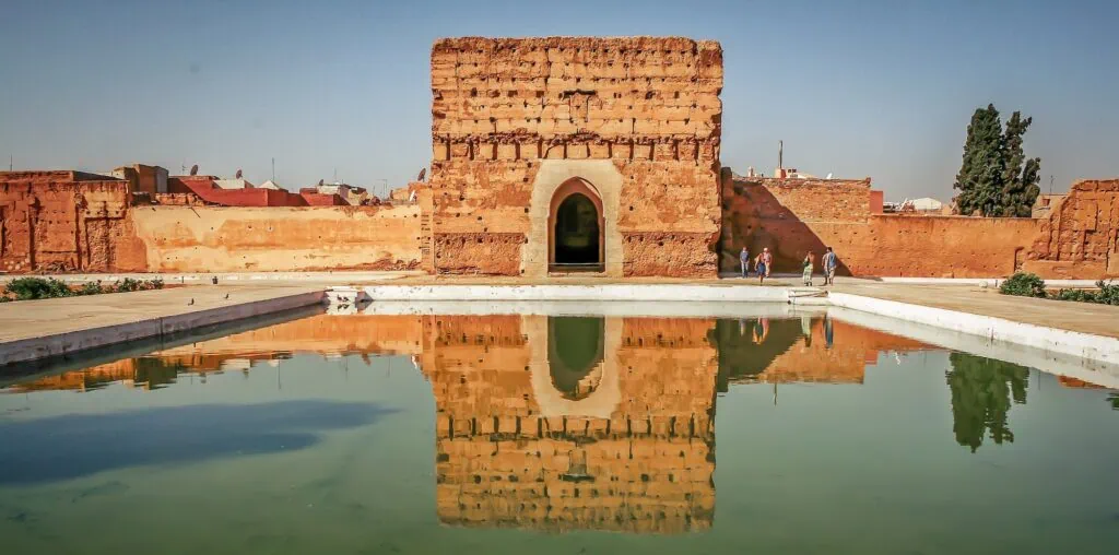 El Badi Palace courtyard with reflecting pool and historic walls with visitors in the background, Marrakesh