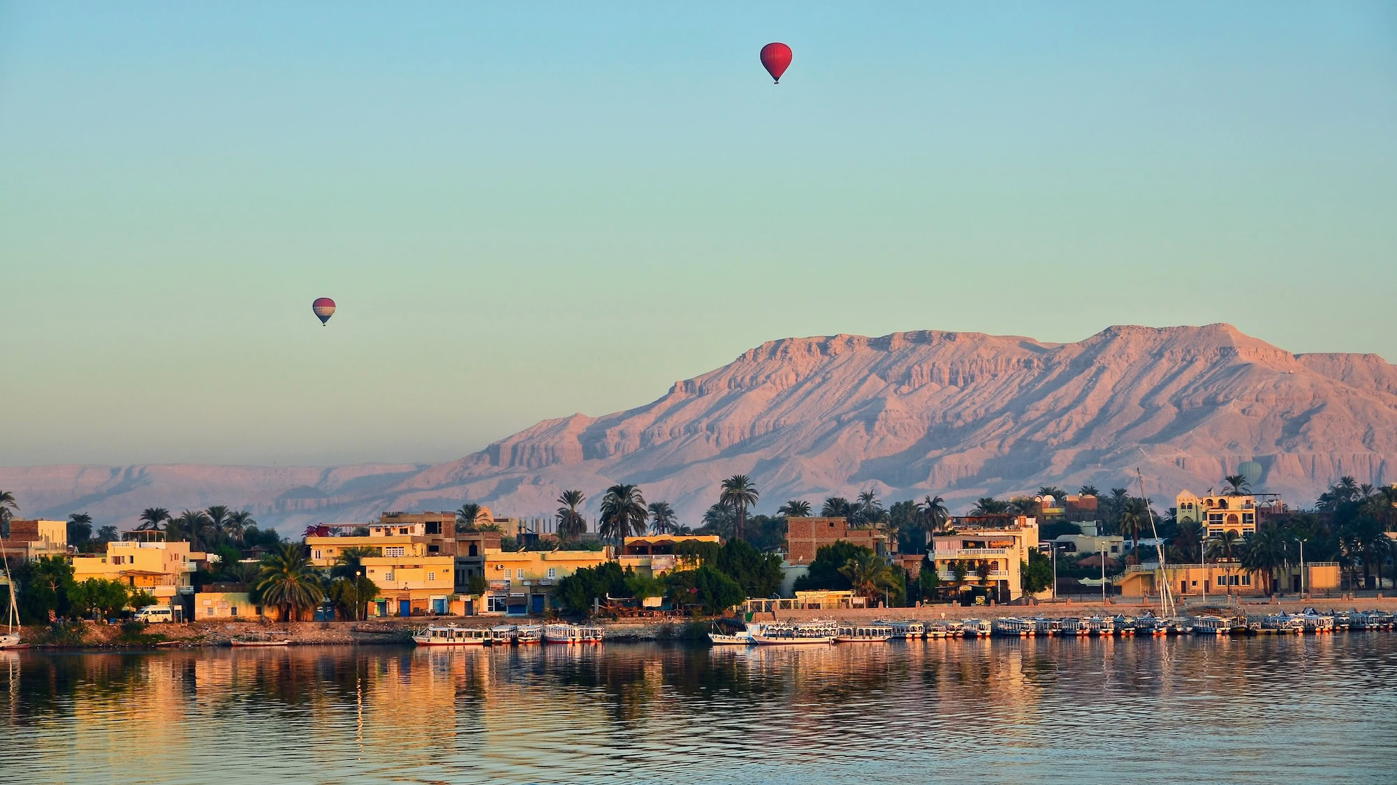 Aerial view of Valley of the Kings with hot air balloons over Nile River and mountains