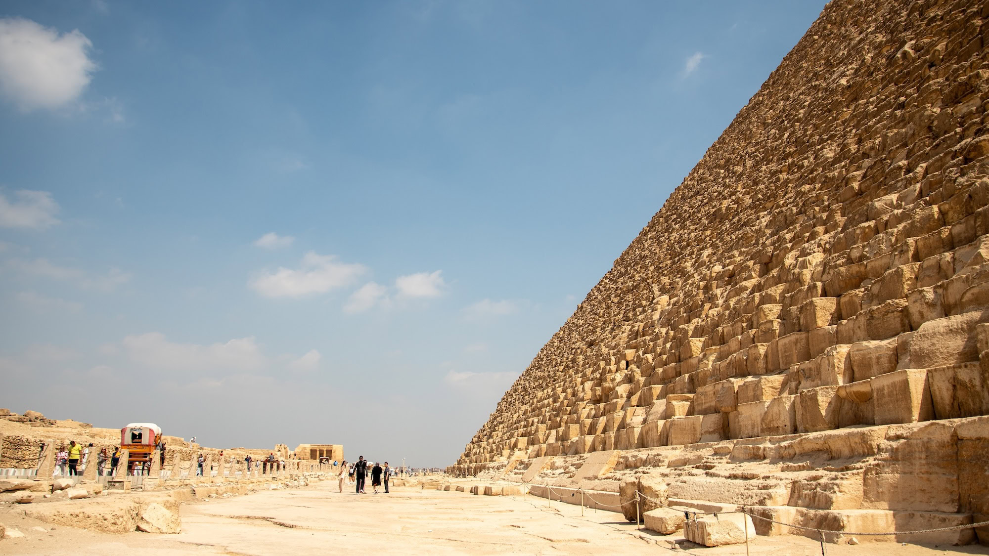 Close-up view of Great Pyramid limestone blocks with tourists for scale