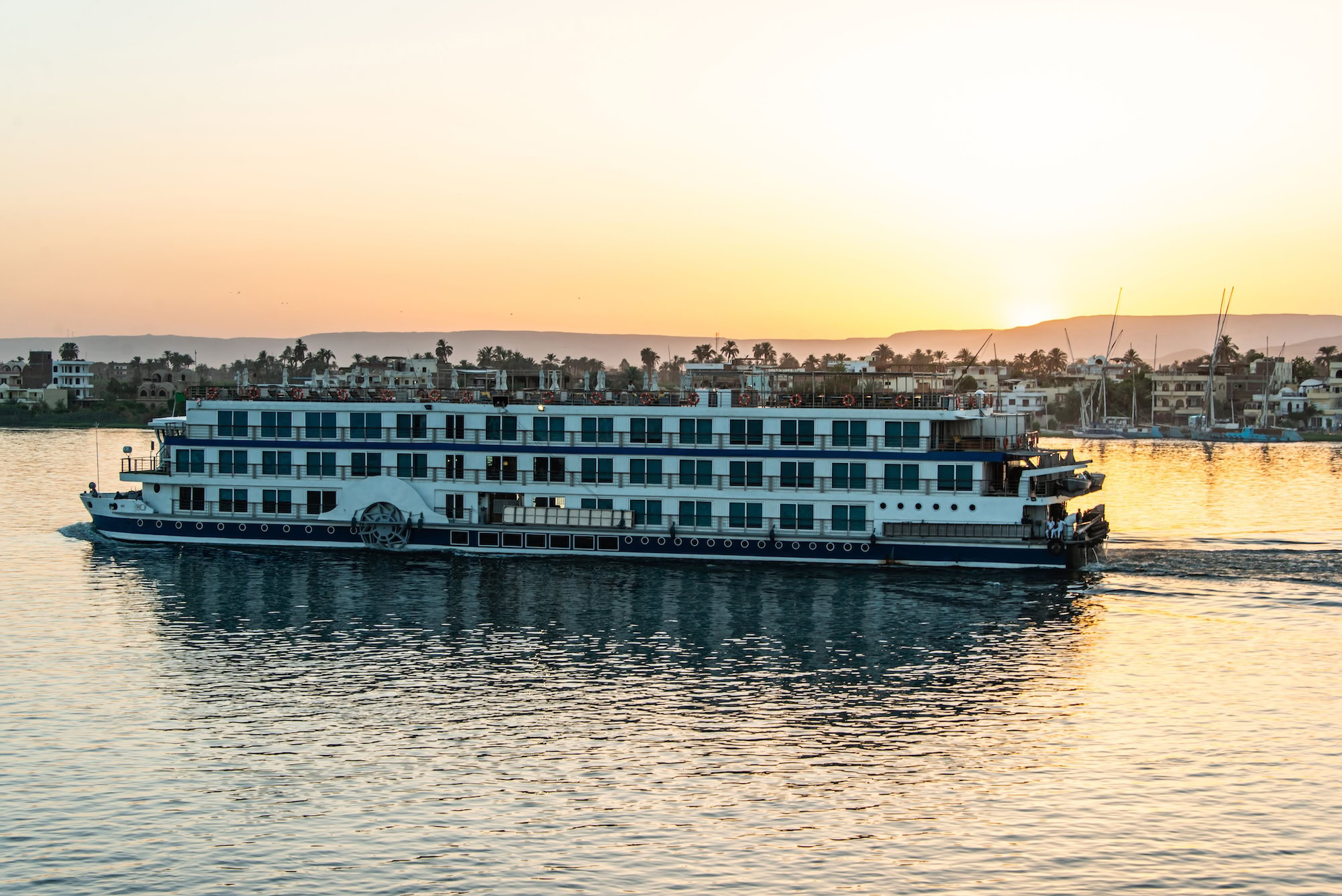 Nile cruise ship with traditional paddle wheel sailing at sunset following ancient routes