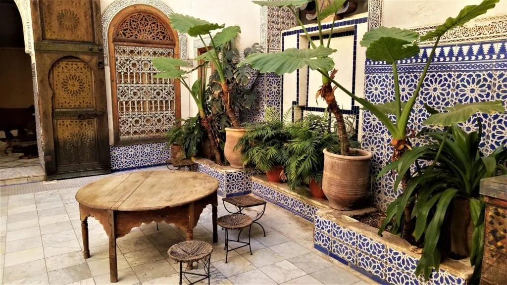 Musée Bert-Flint interior courtyard with patterned tile walls, carved wooden door, and potted plants arranged around a seating area Marrakech