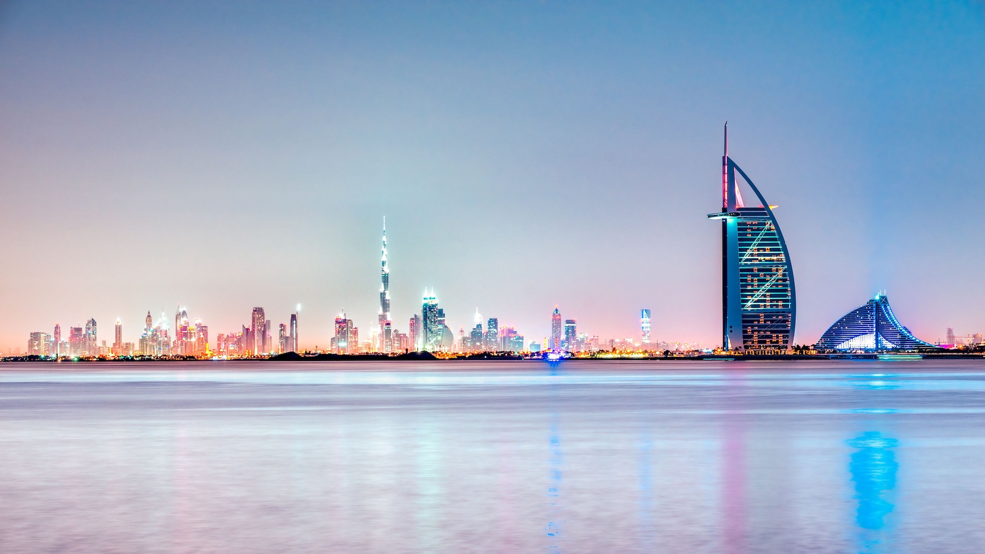 Dubai skyline at twilight with the iconic Burj Al Arab hotel prominently featured