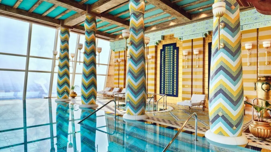 Burj Al Arab indoor pool area with mosaic-covered columns, lounge chairs, and large windows, Dubai
