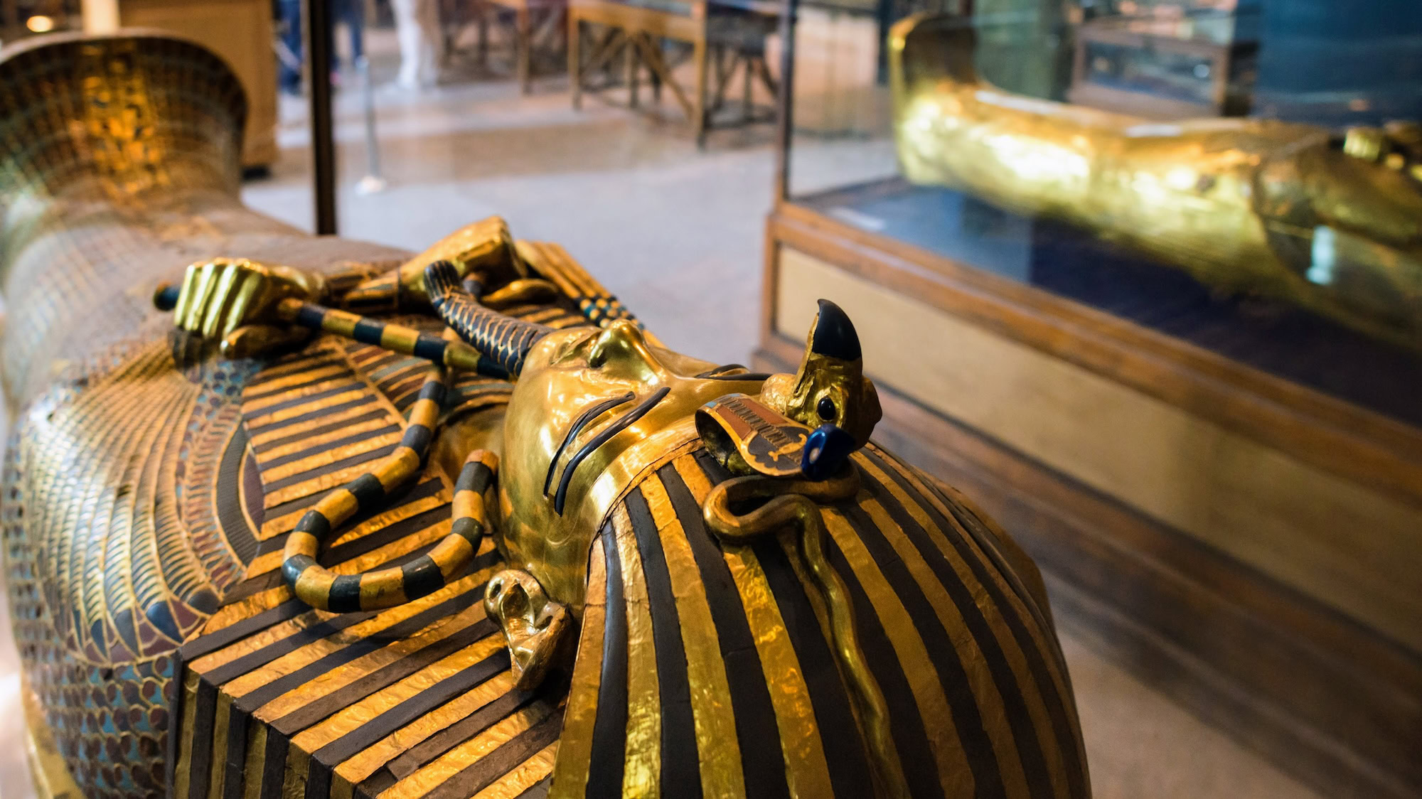 Egyptian sarcophagus and golden artifacts in museum display case