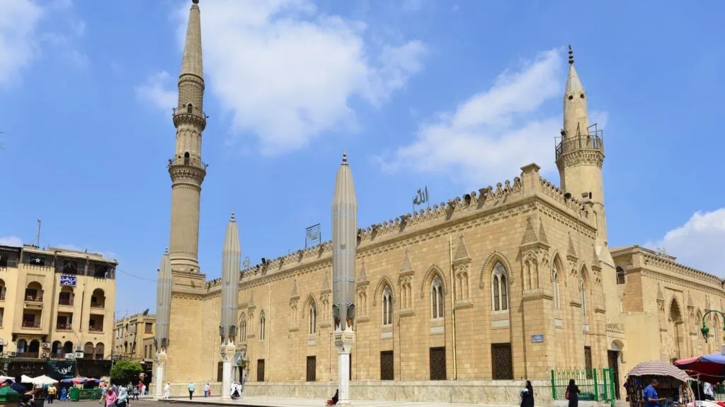 An exterior view showing the facade, arched entrances, and minarets of Al-Hussein Mosque, Cairo