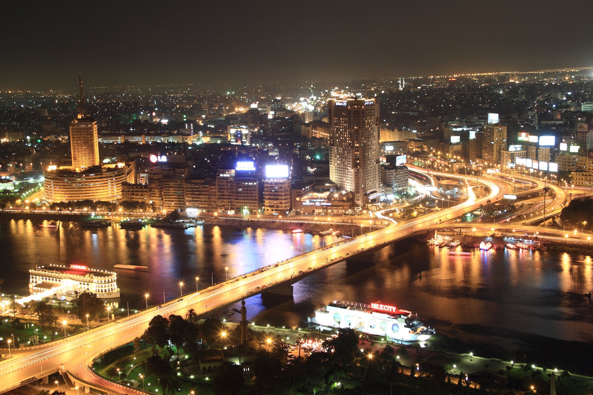 Cairo cityscape with Nile River, modern bridges, and illuminated skyscrapers at dusk