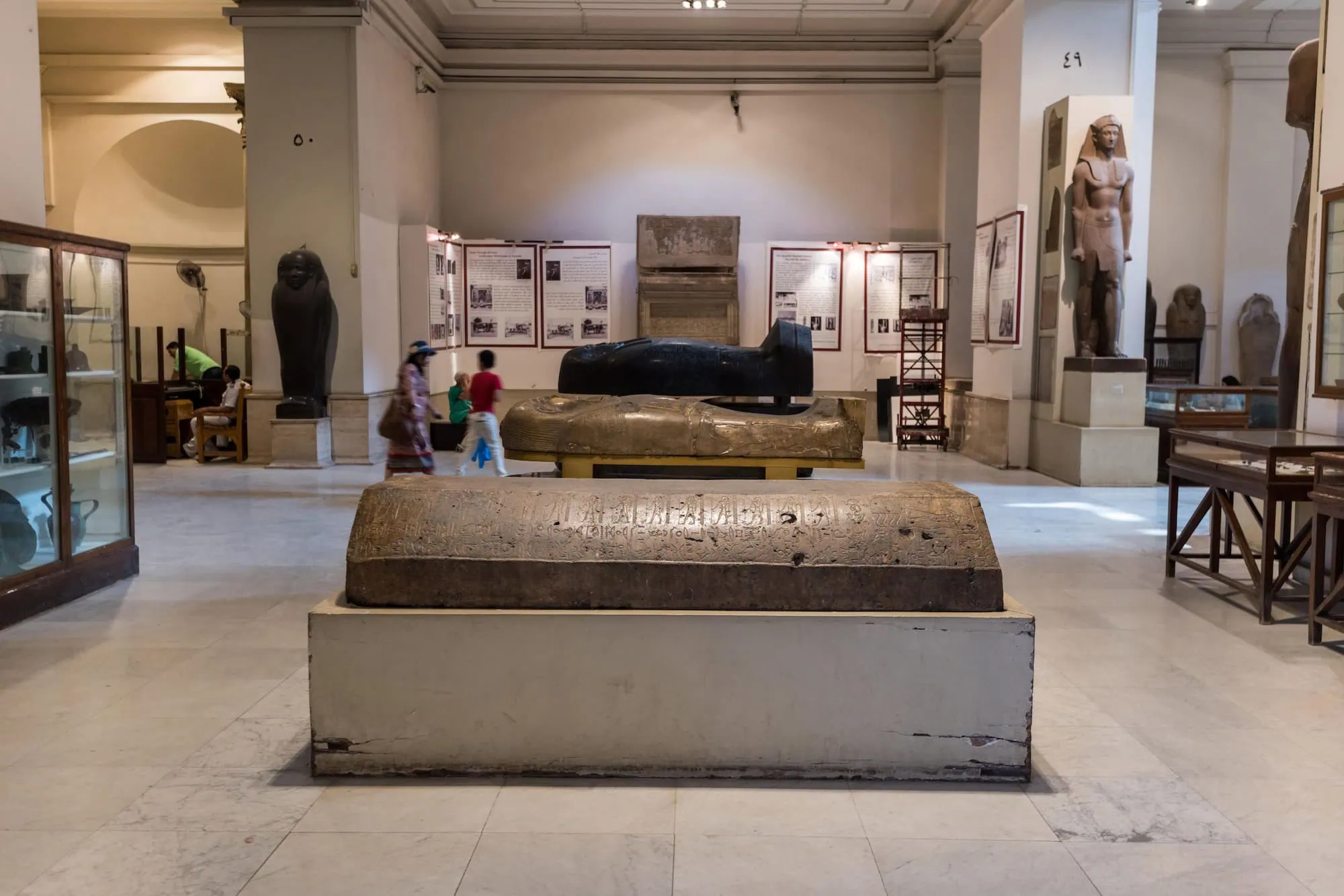 Visitantes explorando el Museo Egipcio con estatuas faraónicas y jeroglíficos antiguos