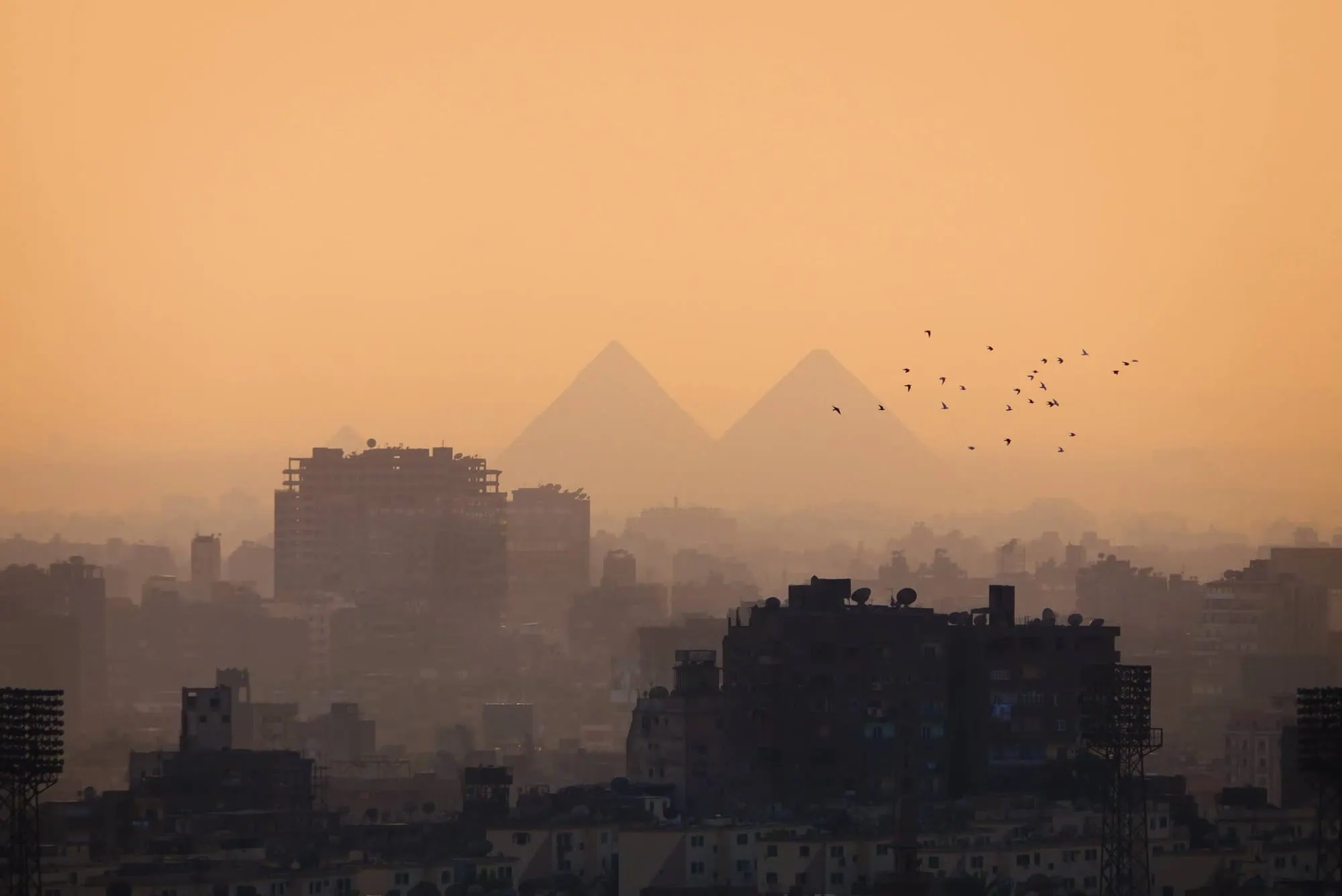 Cairo cityscape showing urban skyline with pyramids in dusty, hazy atmosphere