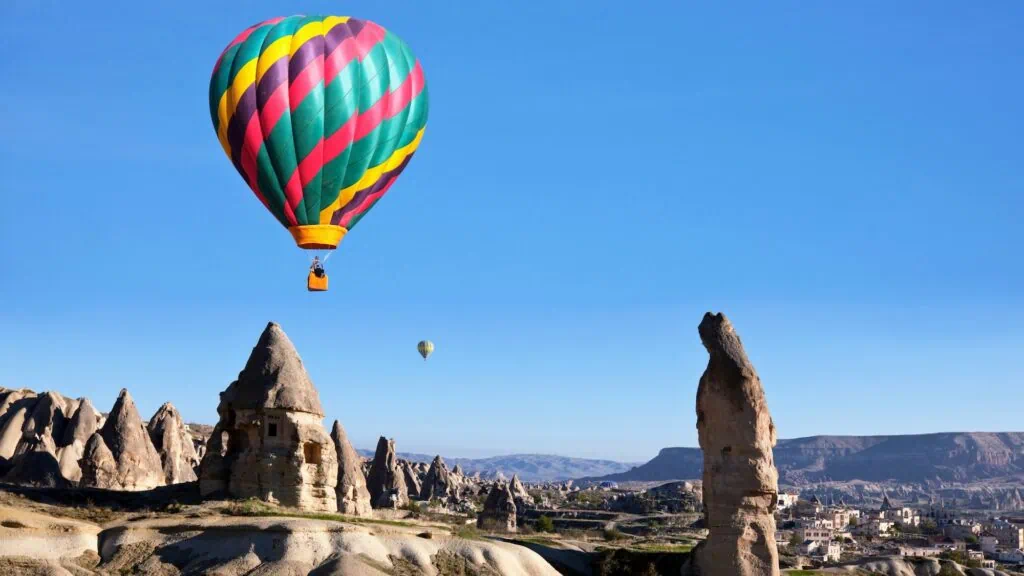 Hot-air balloons rising at sunrise over the rock formations and fairy chimneys of the Cappadocia landscape in central Turkey.