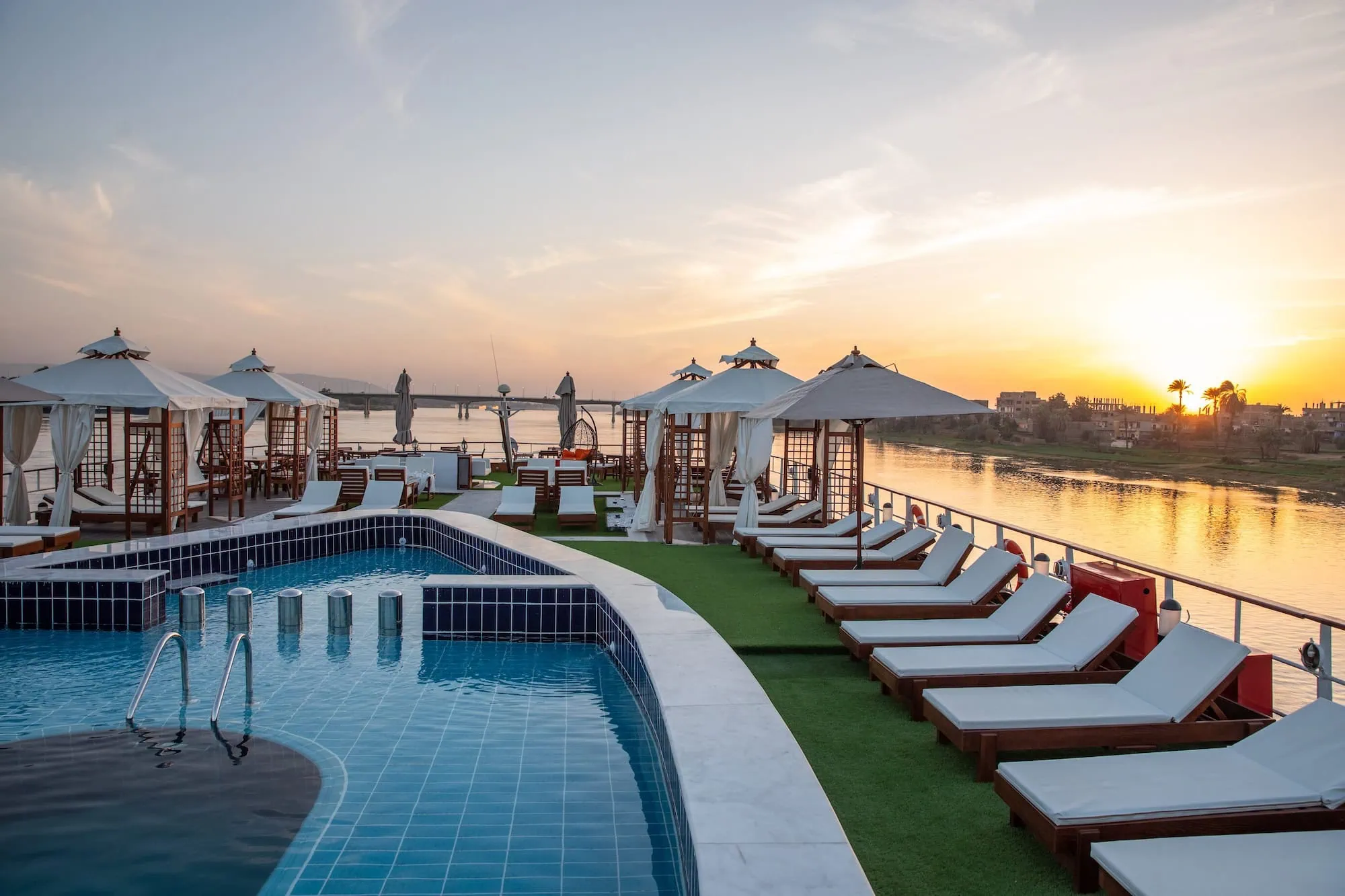 Luxury Nile River cruise ship deck with swimming pool, sun loungers and palm trees