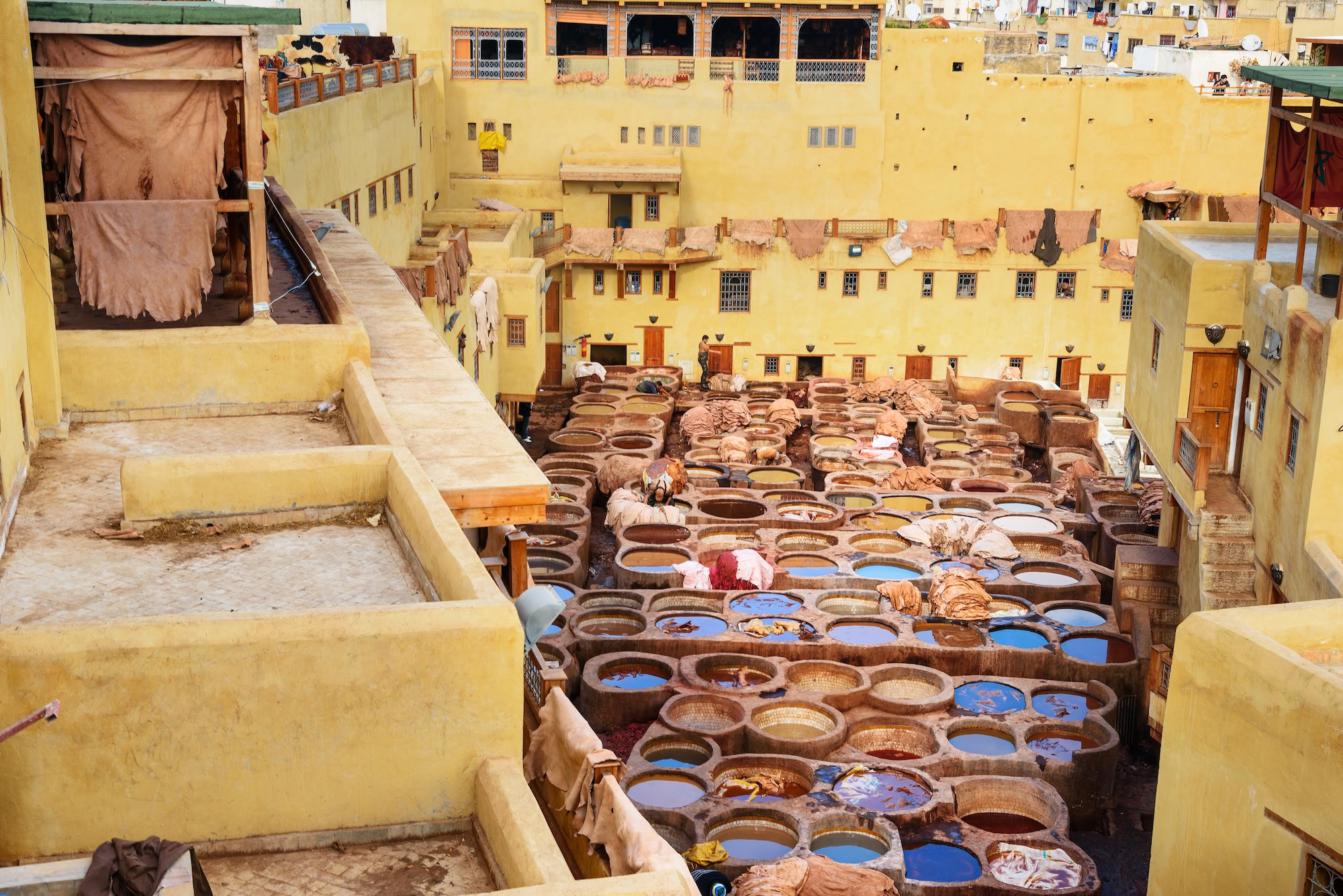 Traditional circular dye vats at Chouara Leather Tannery in Fez medina with colorful dyes