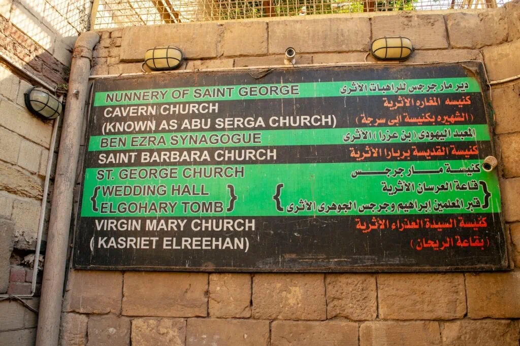 Bilingual Arabic and English street sign pointing to historic churches in the Old Churches district, Coptic Cairo