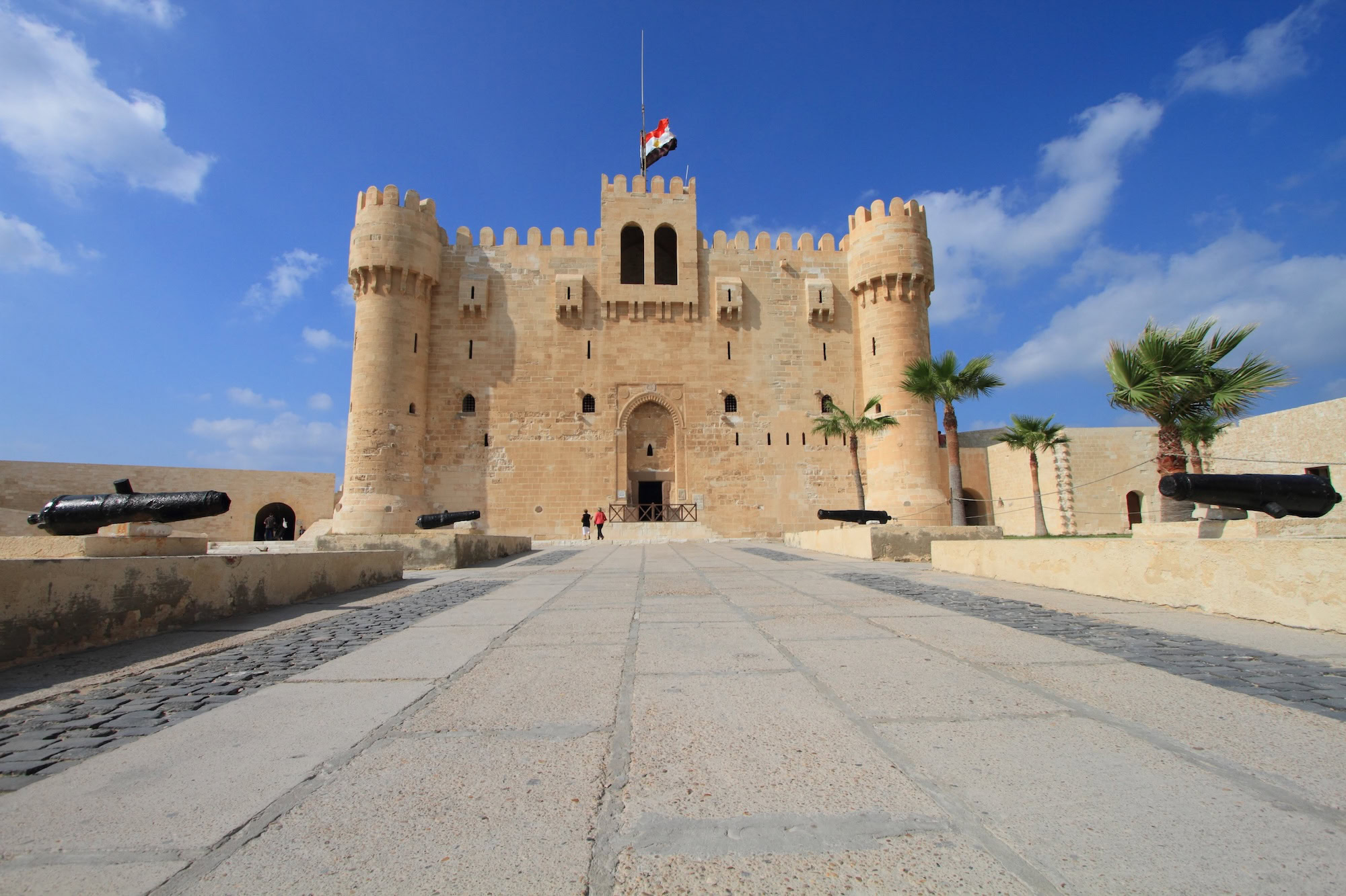 Historic Qaitbay Citadel fortress in Alexandria, Egypt with towers and palm trees