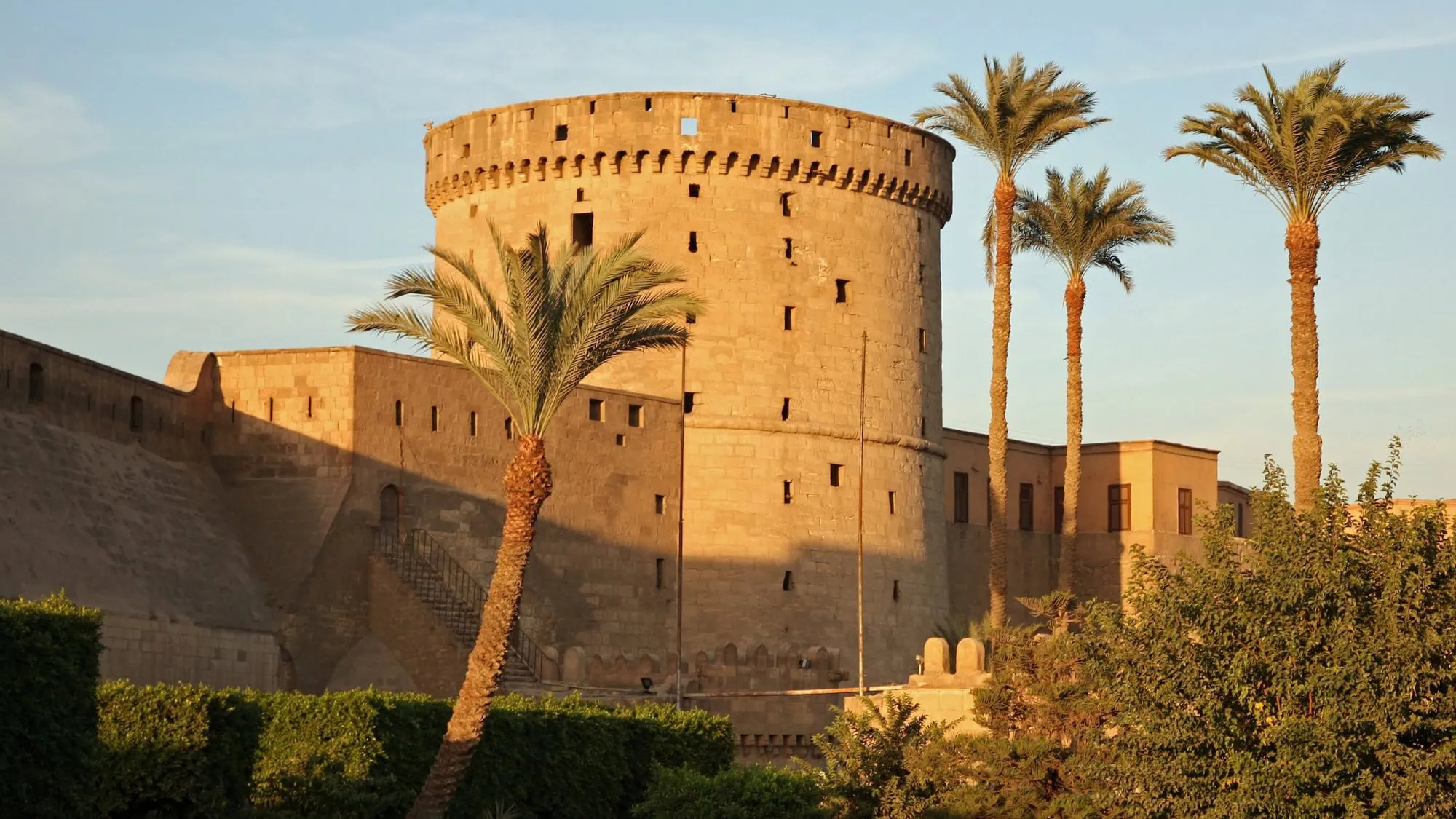 Round defensive tower of Saladin Citadel in Cairo surrounded by palm trees
