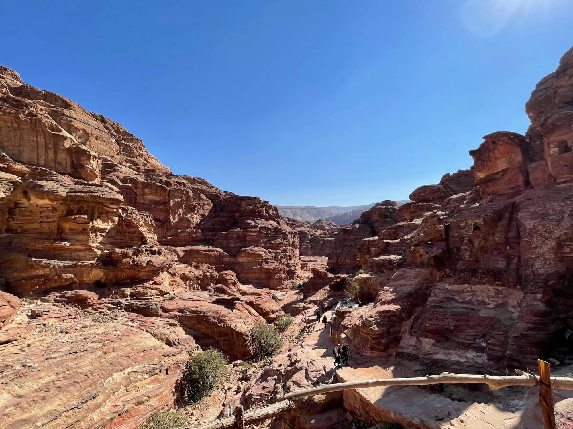 Tourists hiking on wooden-railed trail through Petra's majestic sandstone canyon