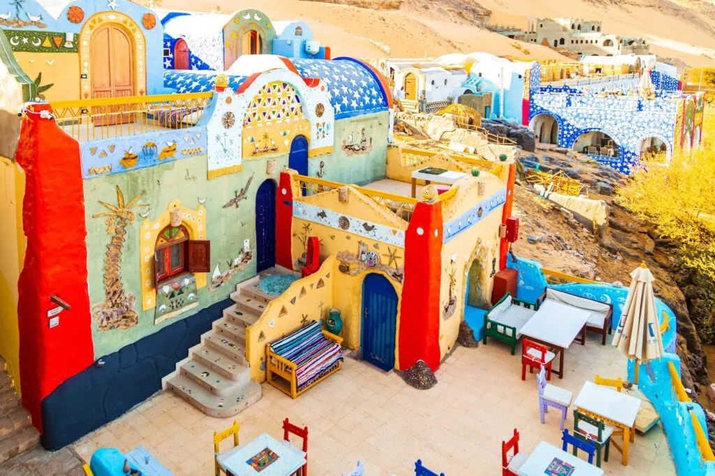 Colourful blue, yellow, and ochre painted houses of a traditional Nubian village on the banks of the Nile near Aswan, Egypt.