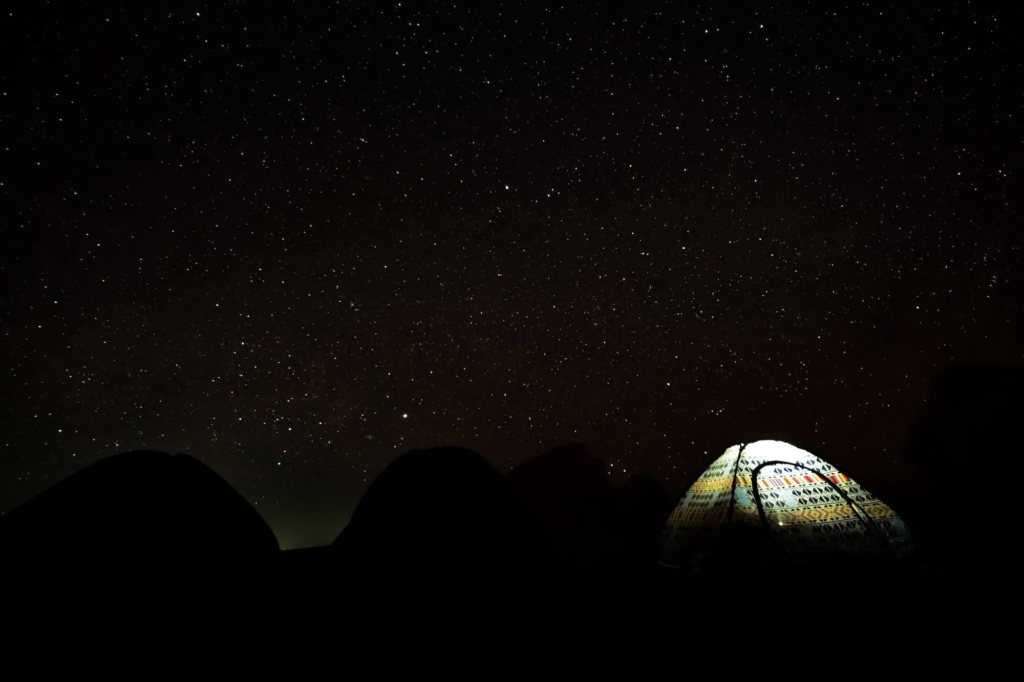 Illuminated camping tents under starry desert sky in White Desert Egypt