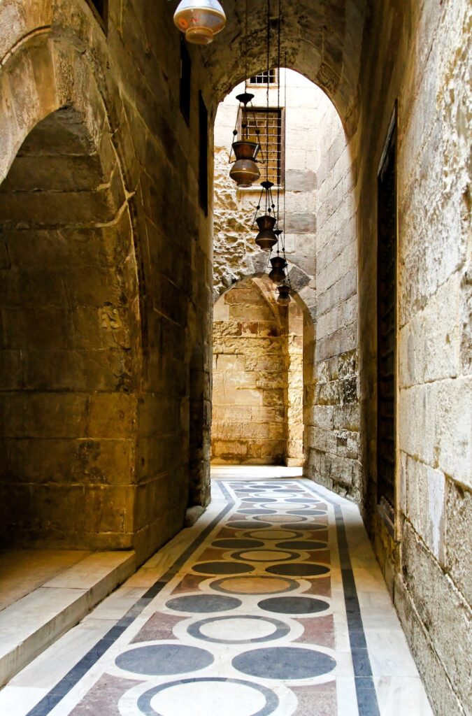 A narrow corridor lined with traditional shops and hanging lamps inside Khan El Khalili market, Cairo