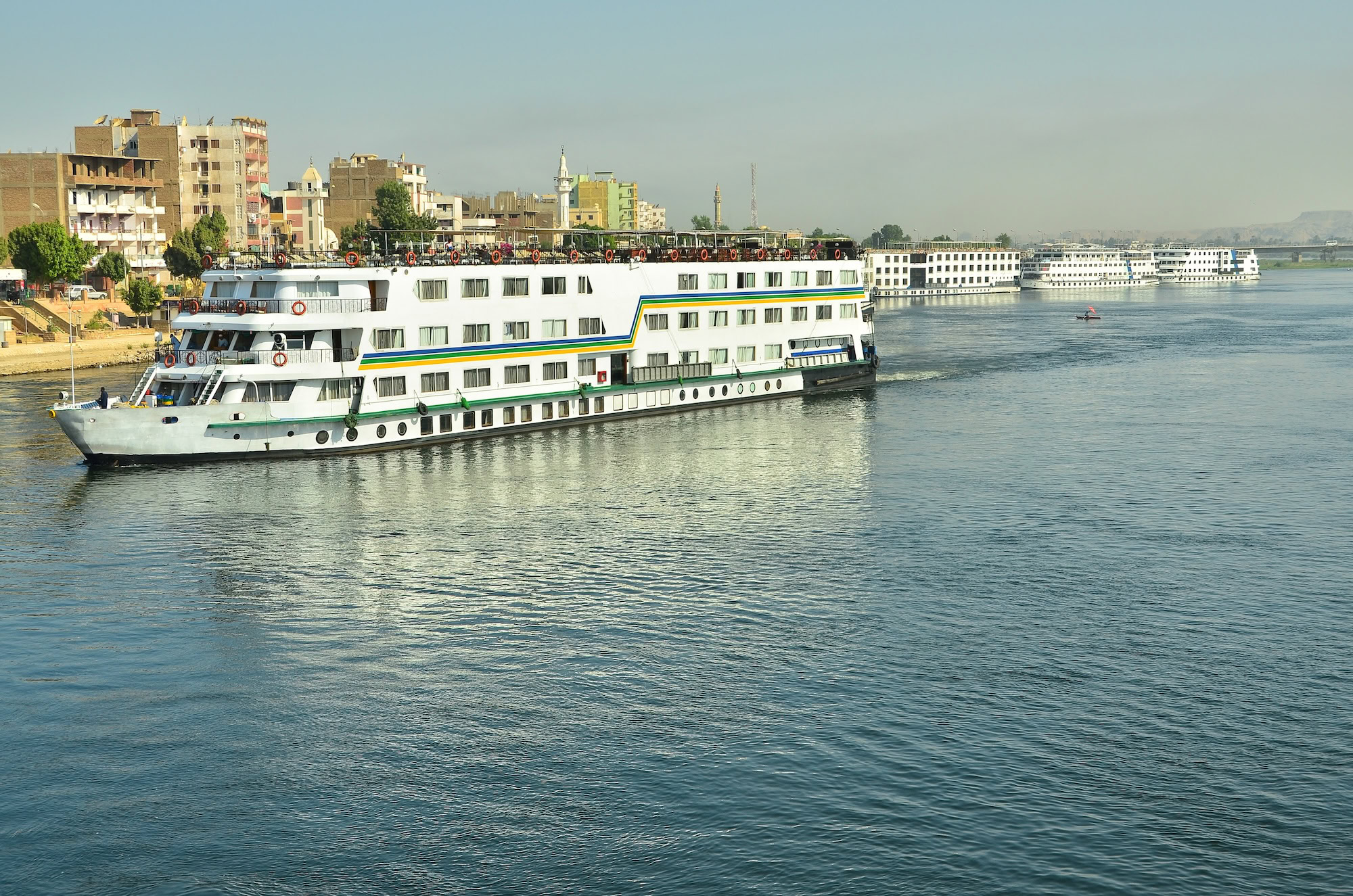 Barcos de cruzeiro no Rio Nilo com céu nublado e margem urbana