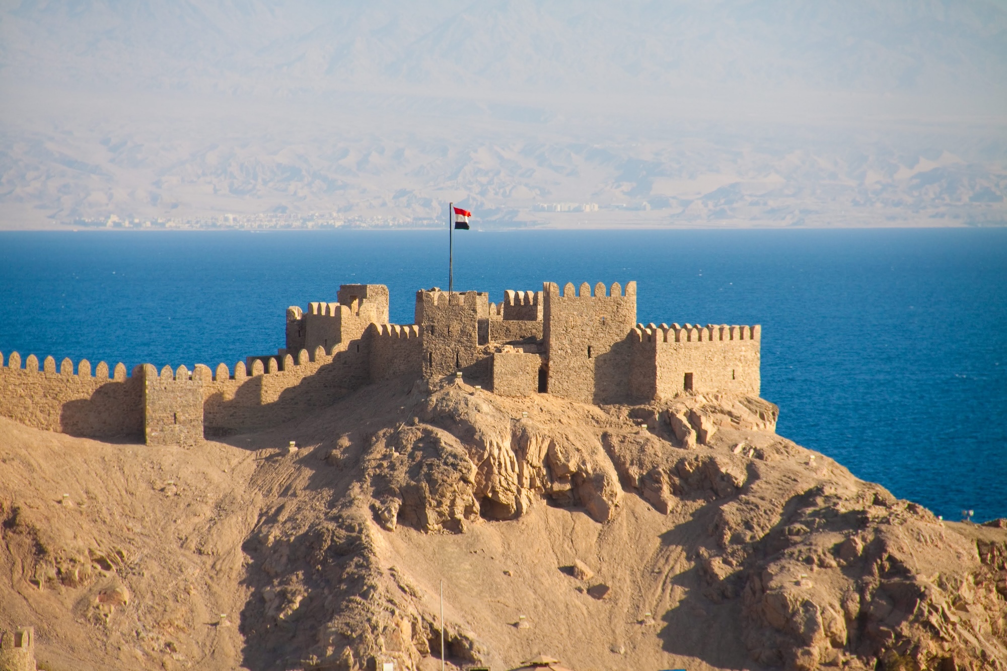 Medieval Crusader fortress with stone walls and towers on rocky coastline overlooking Red Sea