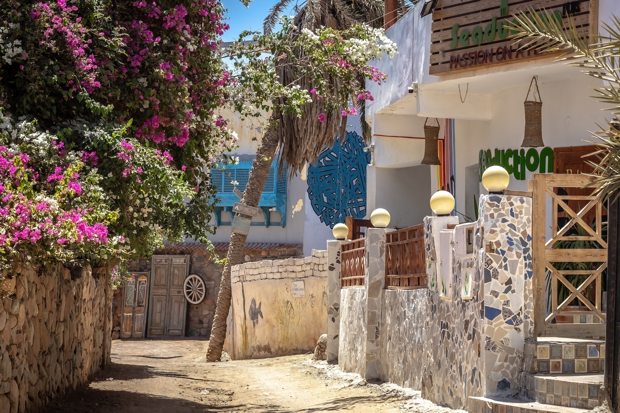 Traditional street scene in Dahab's Assala area with white buildings, shops, and cafes