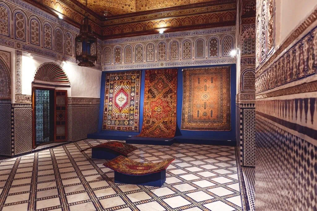 Dar Si Said Museum interior room with patterned tile floors, carved plaster walls, and traditional Moroccan carpets on display Marrakech