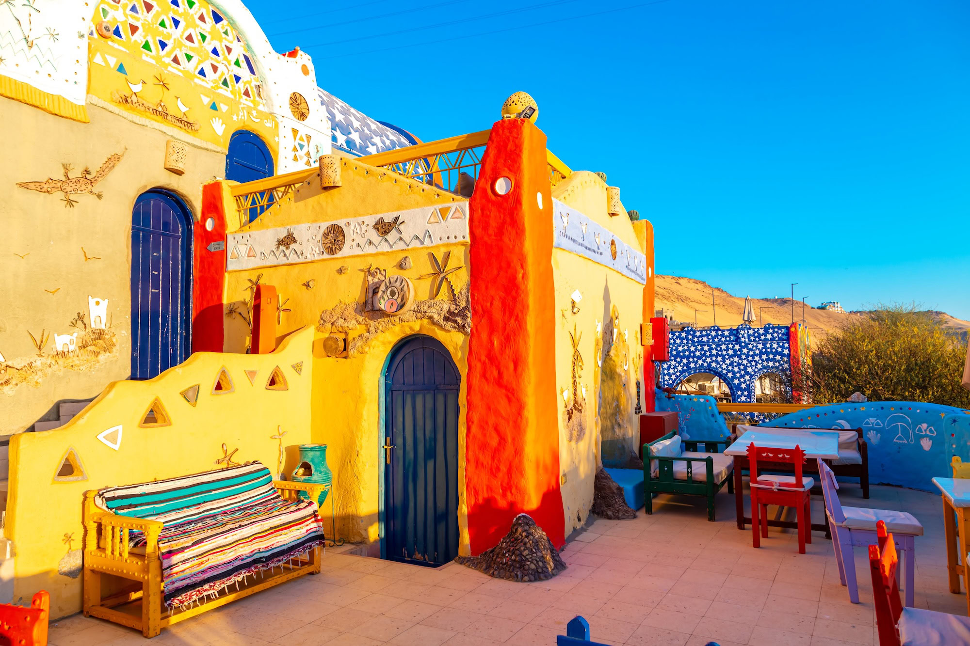 Colorful traditional Nubian village building with decorative murals and striped outdoor seating