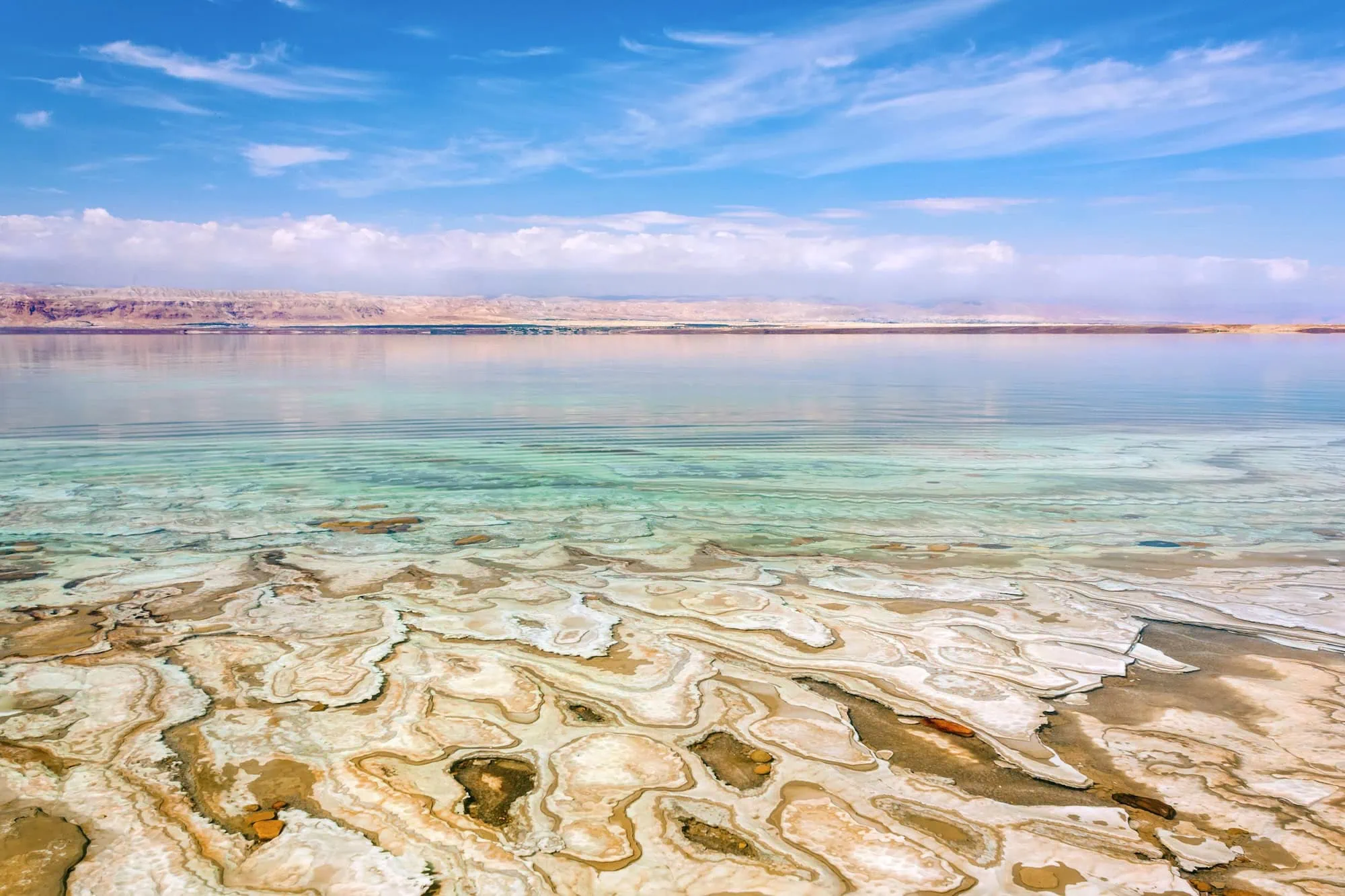 Dead Sea salt formations and mineral deposits along the turquoise shoreline with mountains