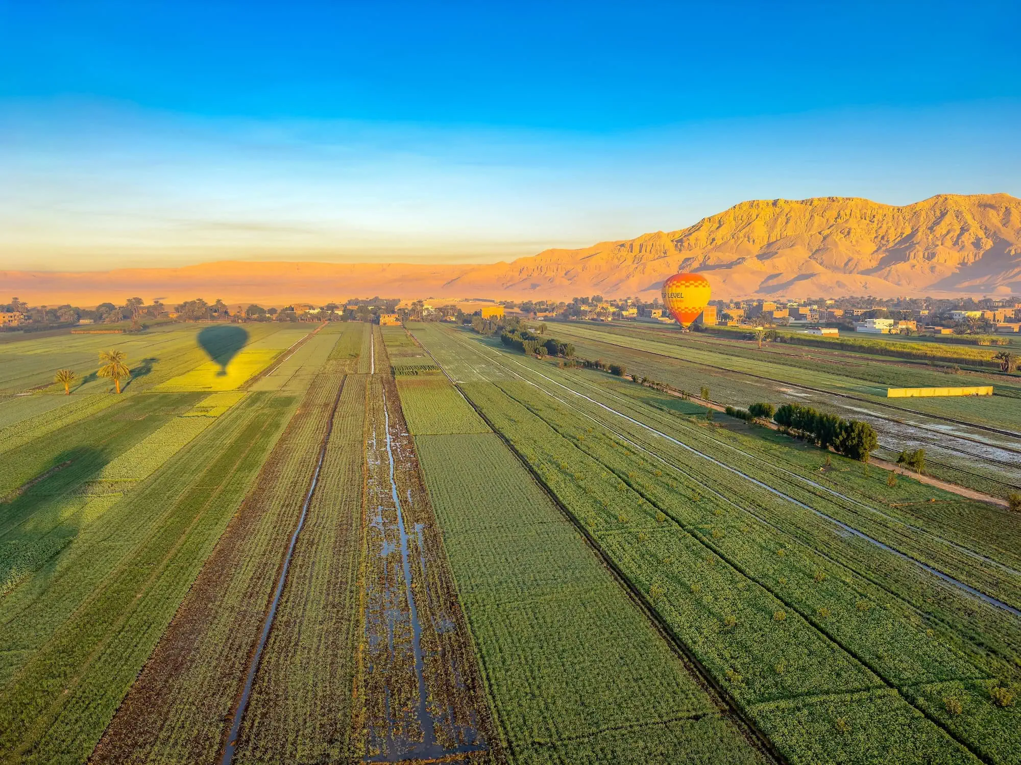 Aerial view of Luxor agricultural area with hot air balloons floating over farmland and mountains