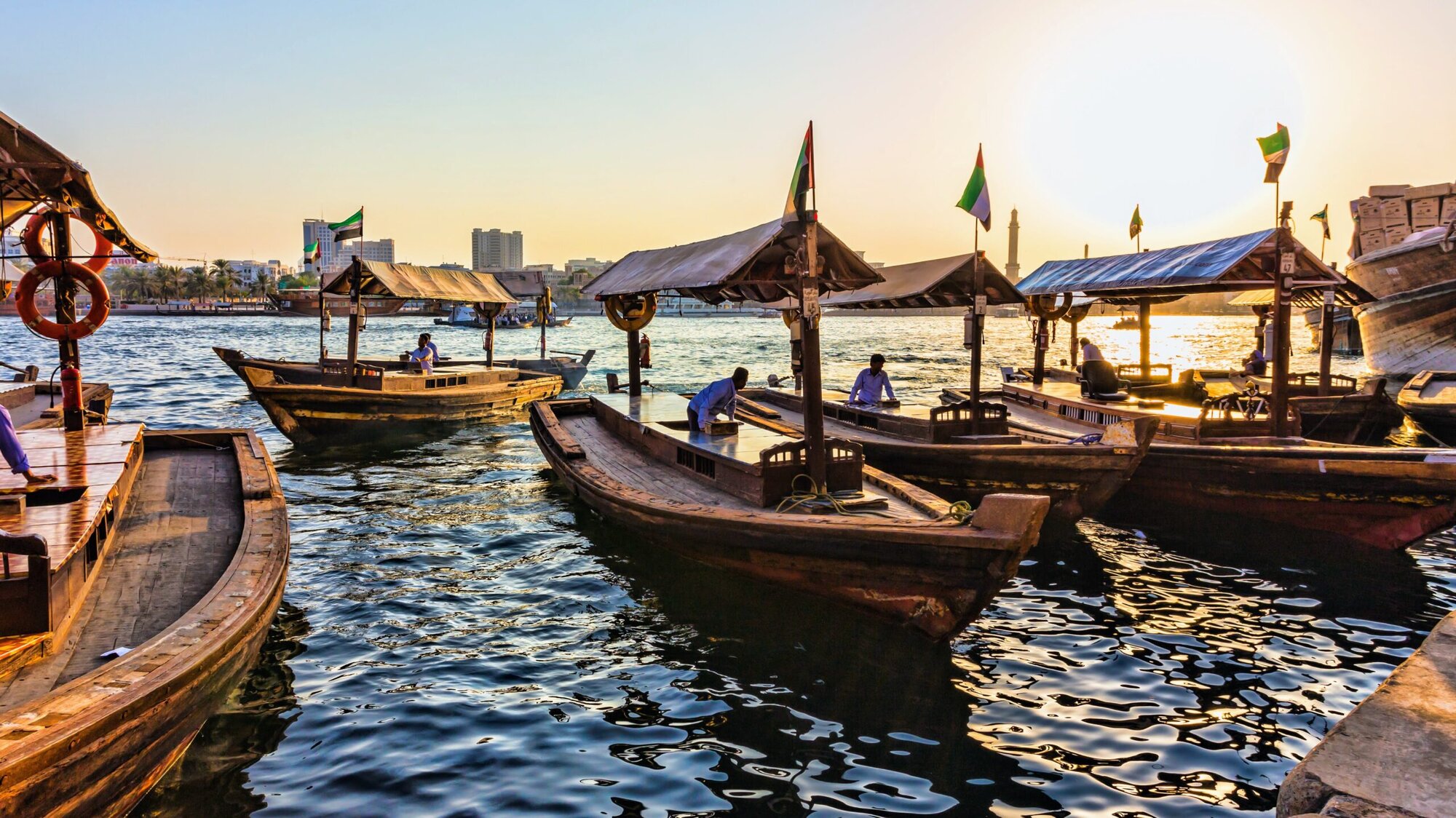 Traditional Abra boats docked at Dubai Creek waterfront with city skyline