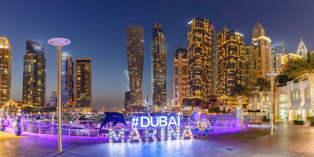 Dubai Marina logo and Harbour skyline architecture wealth luxury travel panorama at night in United Arab Emirates modern