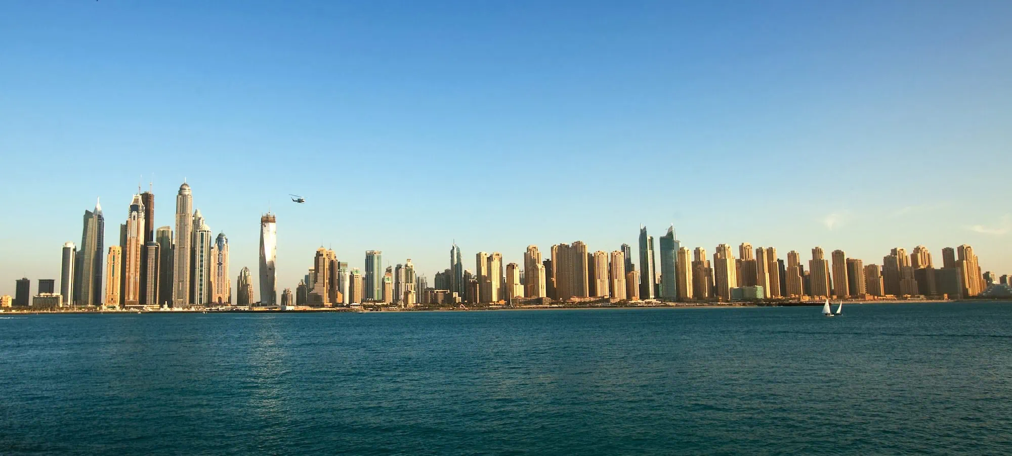 Aerial view of Dubai Marina skyline with helicopter and boats showing transportation options