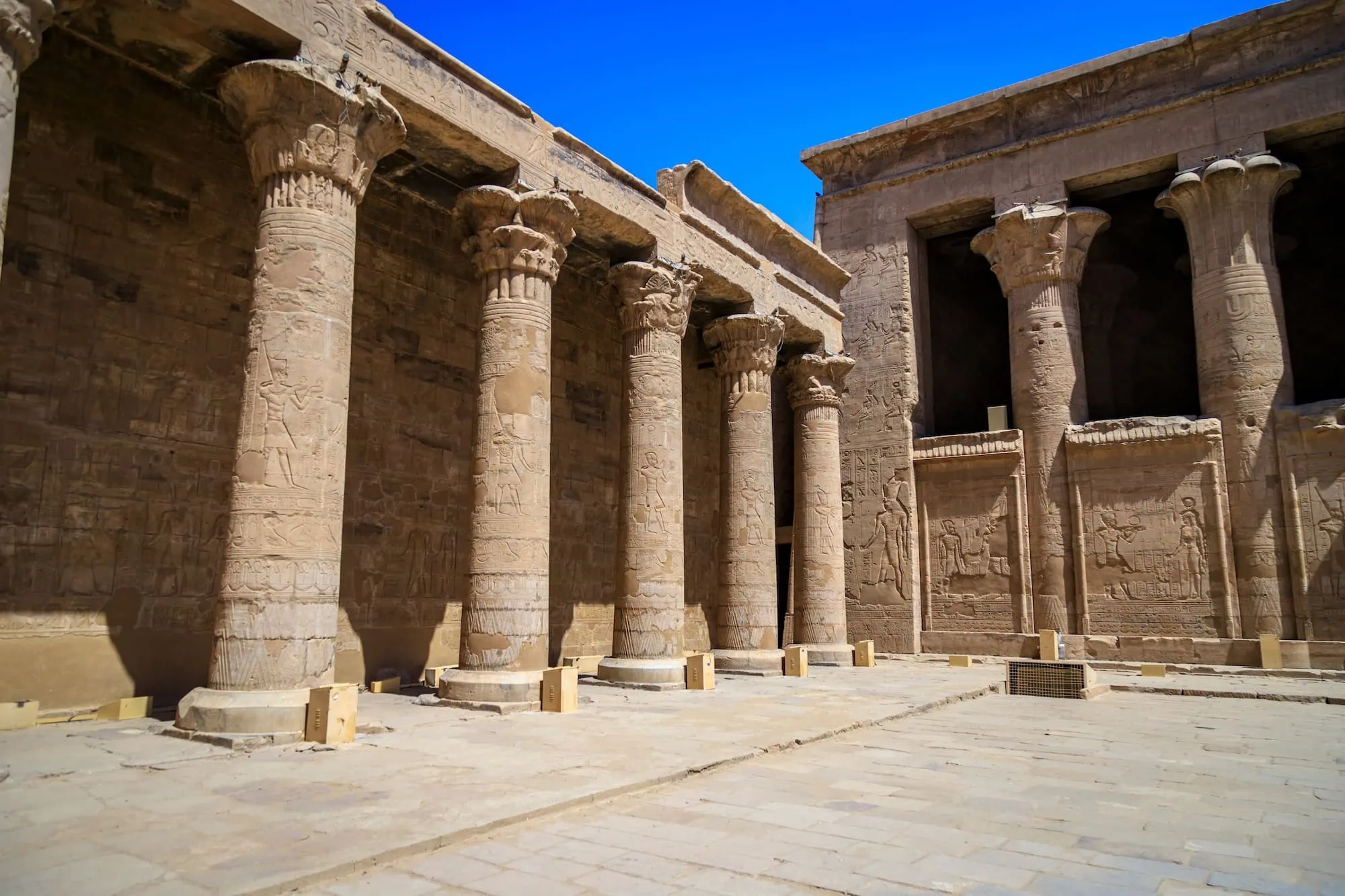 Interior view of Edfu Temple showing intact columns with hieroglyphs and carved capitals under preserved roof