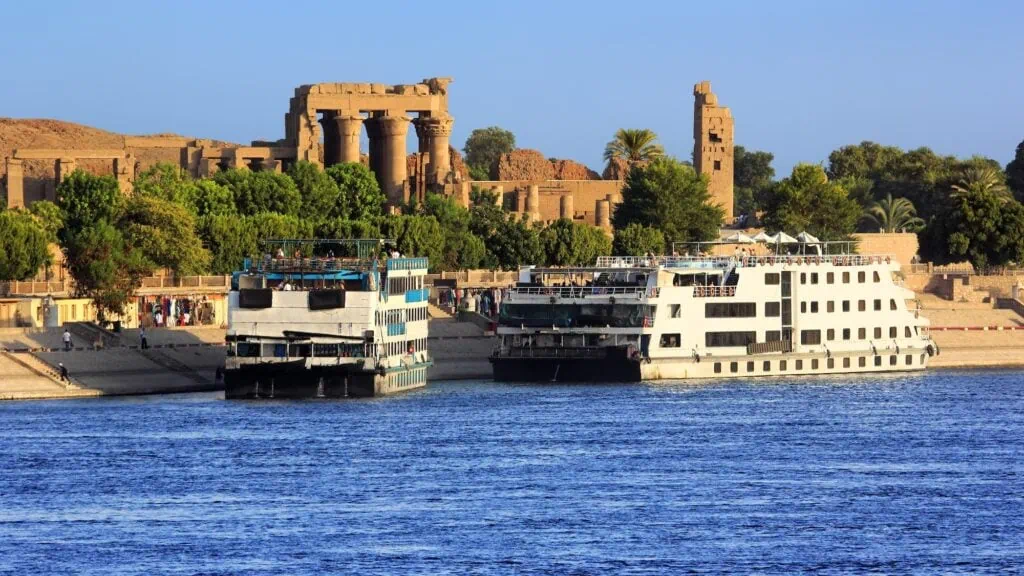Cruise ships docked along the Nile with the colonnade of the Hypostyle Hall at the Temple of Kom Ombo in the background, Kom Ombo